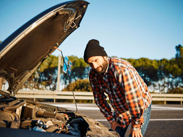 Ein Erwachsener beugt sich zur aufgeklappten Motorhaube nieder.  Motorschaden. 